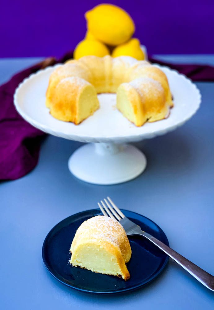 pastel de limón airfryer en un plato de pastel blanco con limones frescos