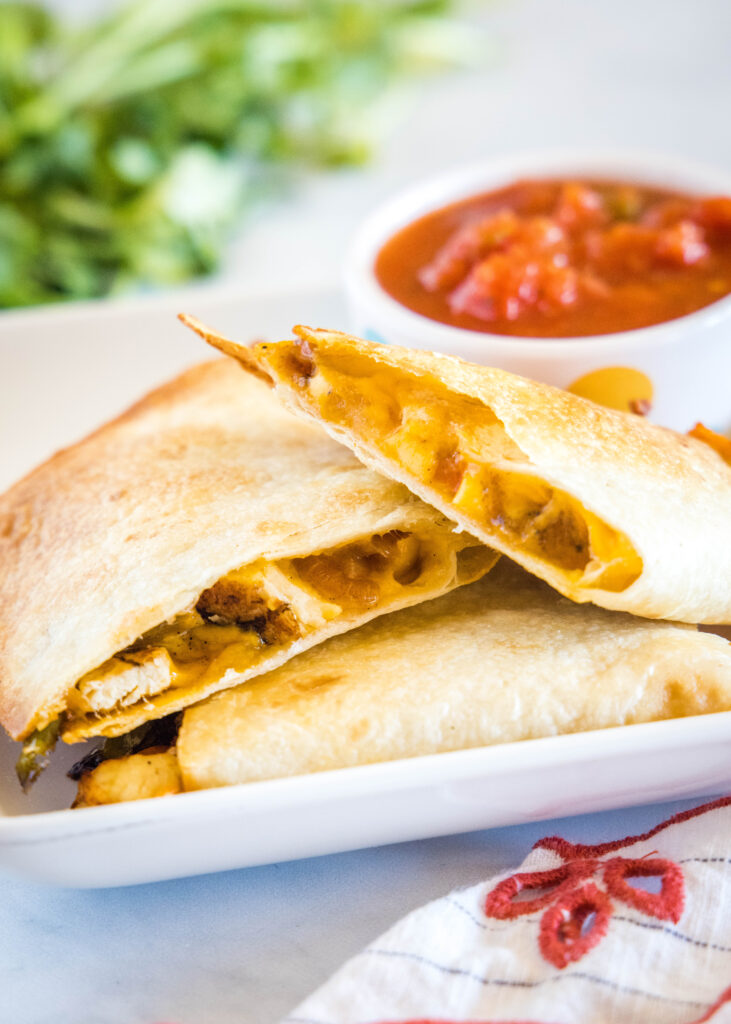 Quesadillas de freidora en rodajas en un plato blanco con un plato de salsa