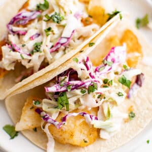 primer plano de tacos de pescado con ensalada de col encima.